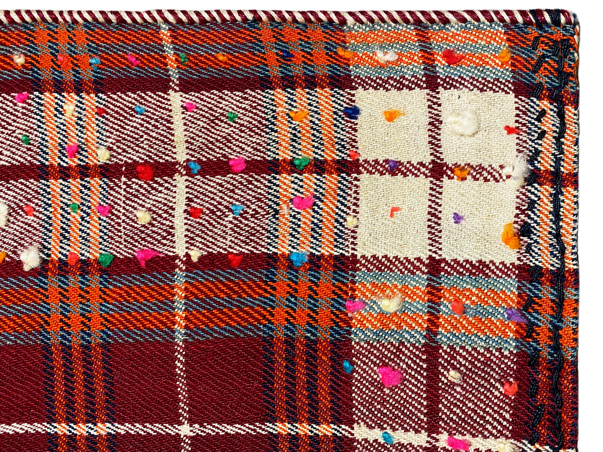 Gros plan : tissu de tapis à motif écossais, points de couleur vive et bordure multicolore