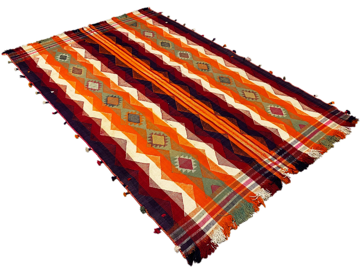 Tapis Jajim vu en biais du dessus, motifs en zigzag et à rayures orange et bleu foncé