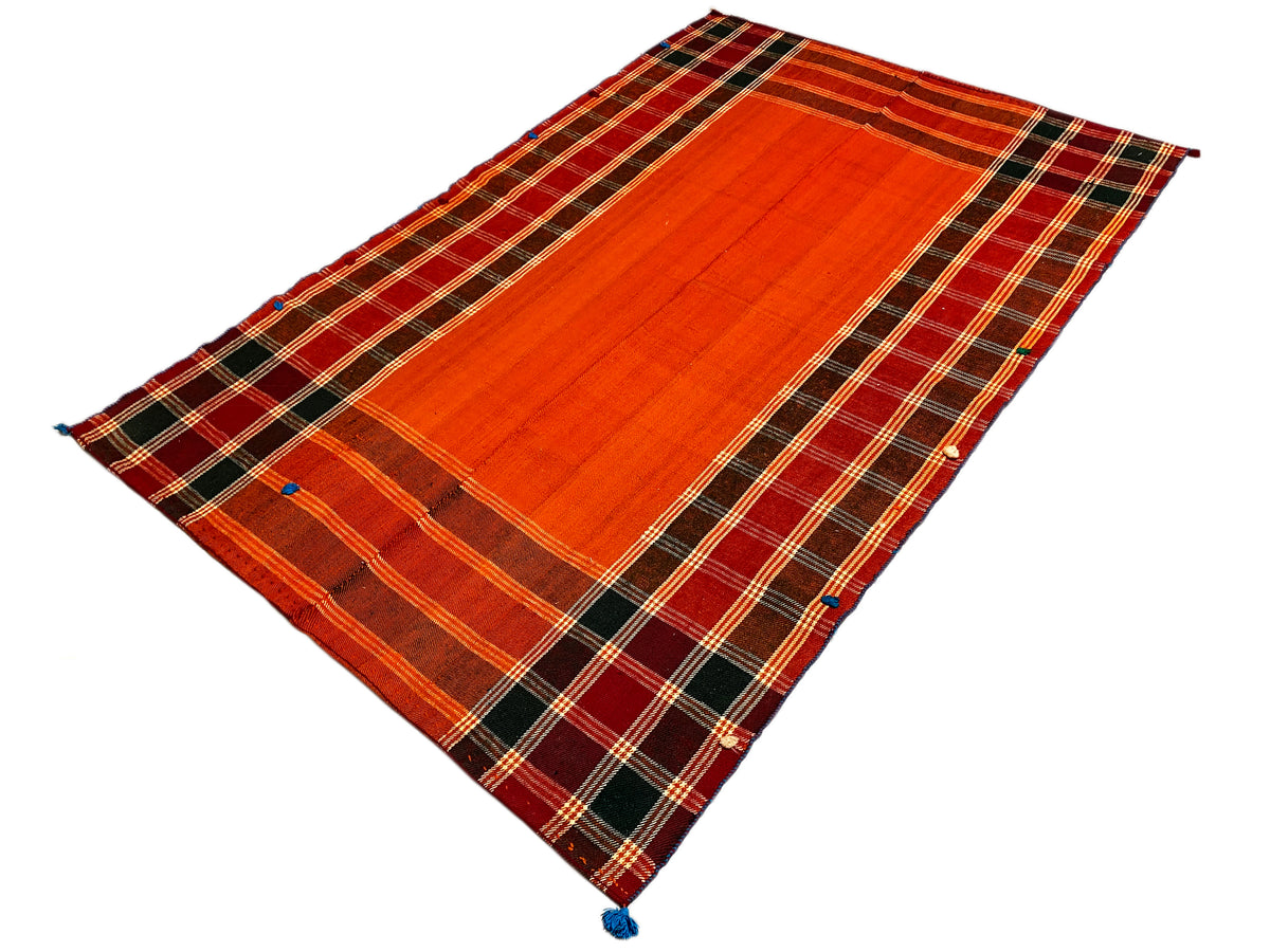 Tapis Jajim rouge-orange et brun foncé : bandes à carreaux diagonales, coins ornés de pompons bleus