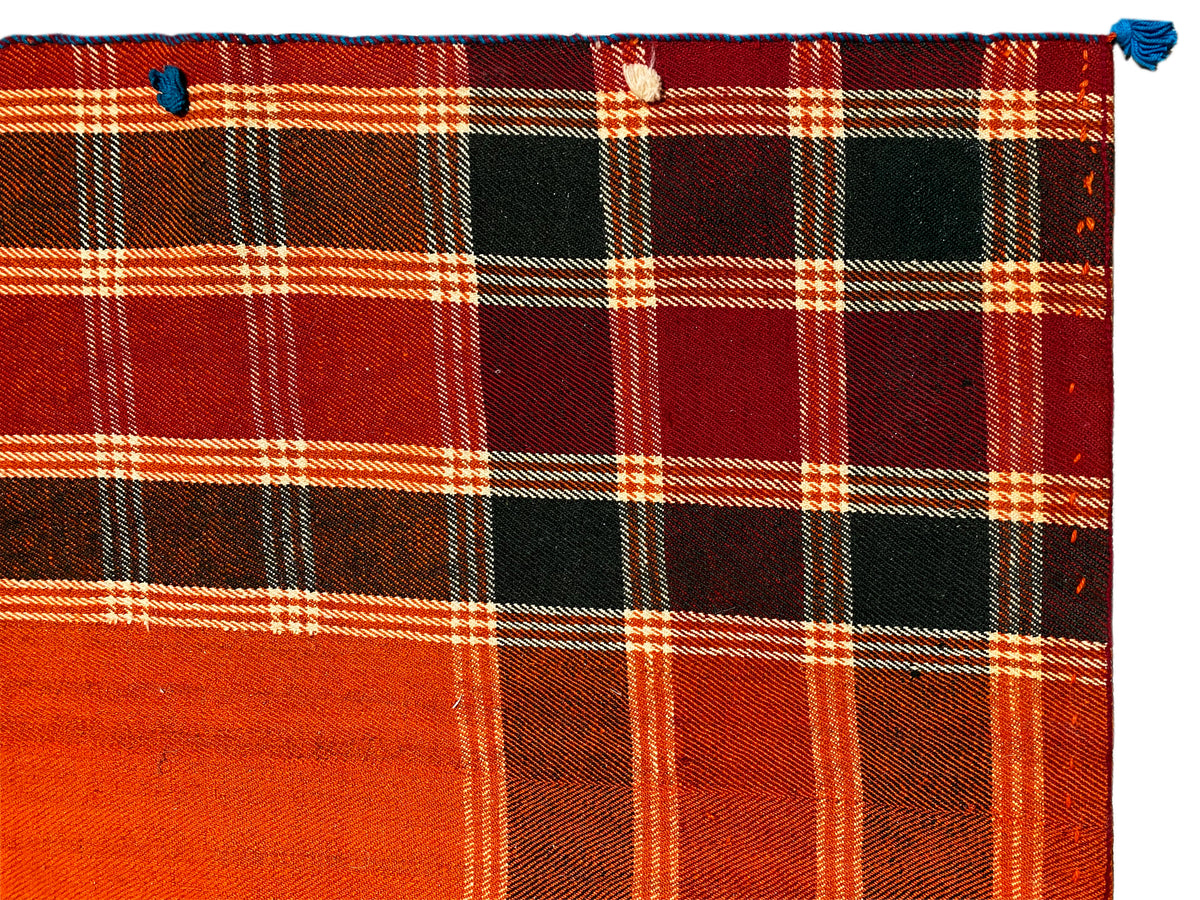 Détail du tapis Jajim : motif à carreaux rouge orangé vif avec des aplats noirs et des lignes blanches