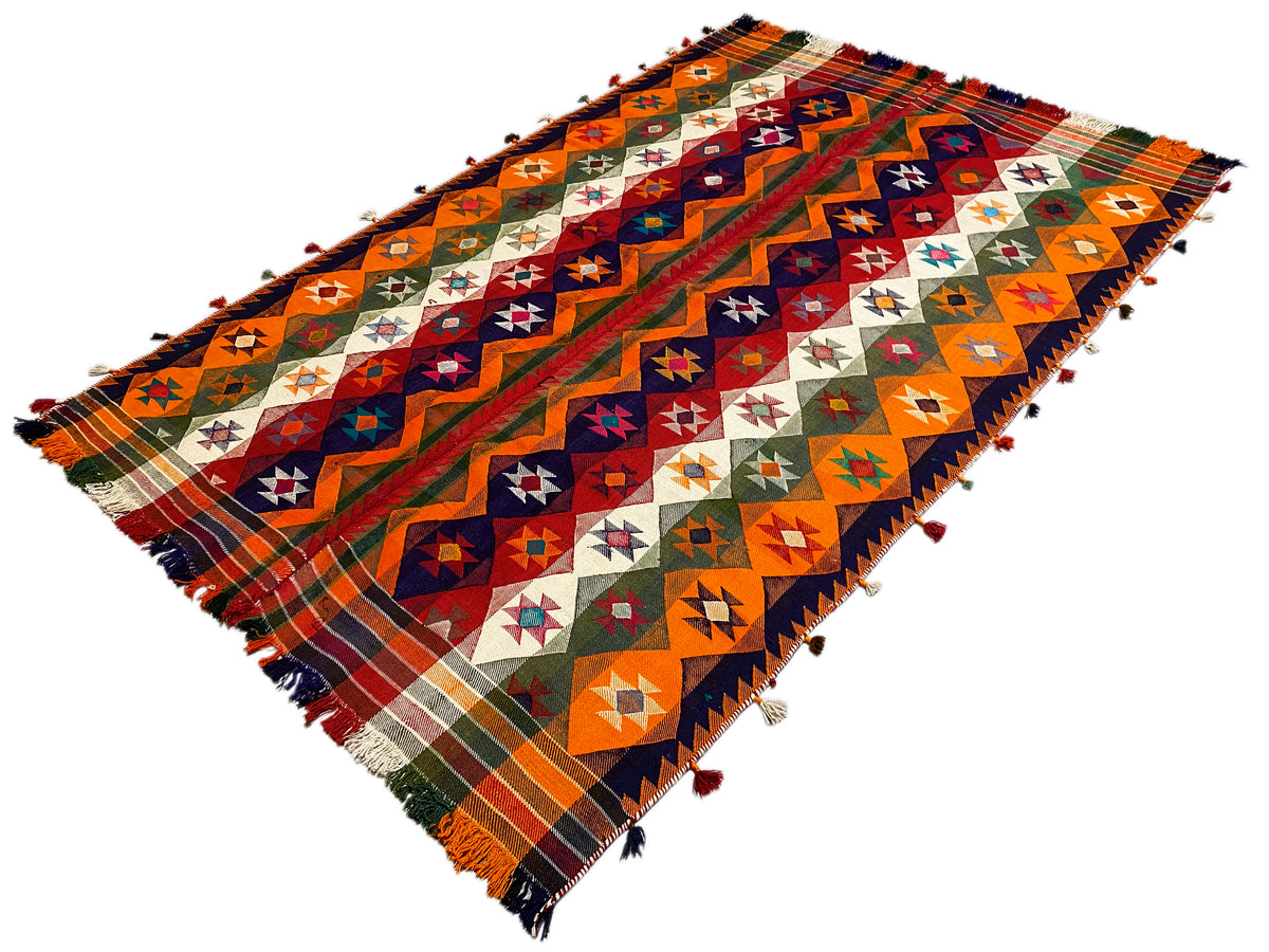 Tapis Jajim vue diagonale : formes géométriques orange, bleues et vertes, franges