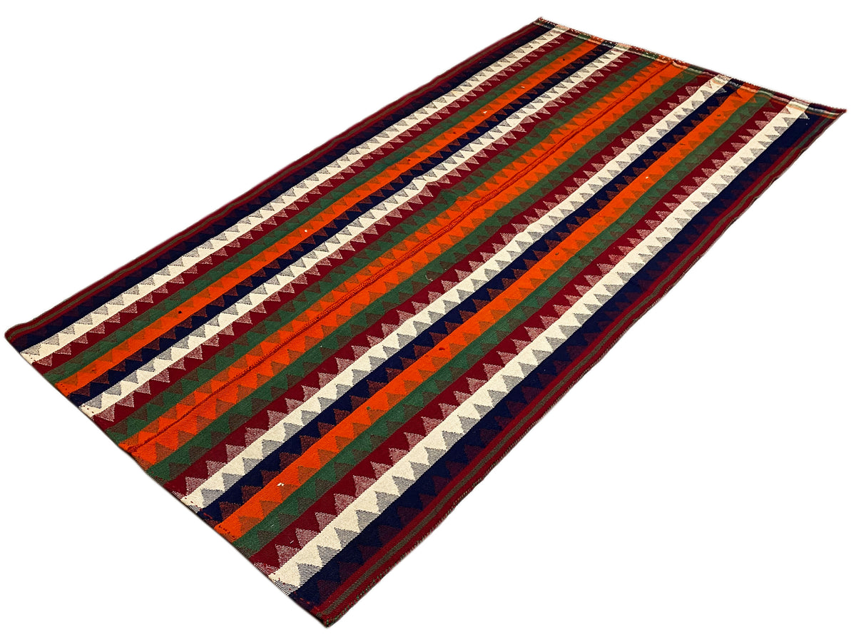 Tapis jajim posé à plat : motif de rayures diagonales en vert, rouge, bleu et crème