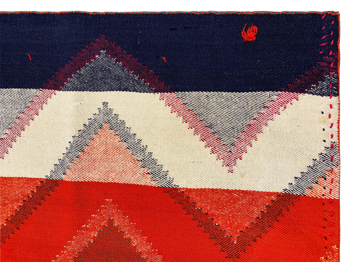 Bord de tapis avec couture et motif géométrique en bleu foncé, crème, rouge et gris