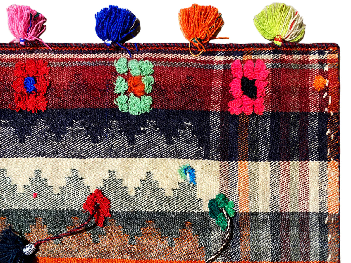 Gros plan : tapis jajim à motif à carreaux, motifs floraux et glands multicolores