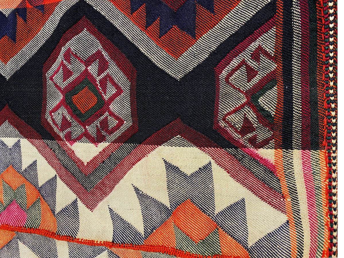 Détail du tapis jajim : ornement en losanges et motif en zigzag sur le bord, en rouge, noir et crème