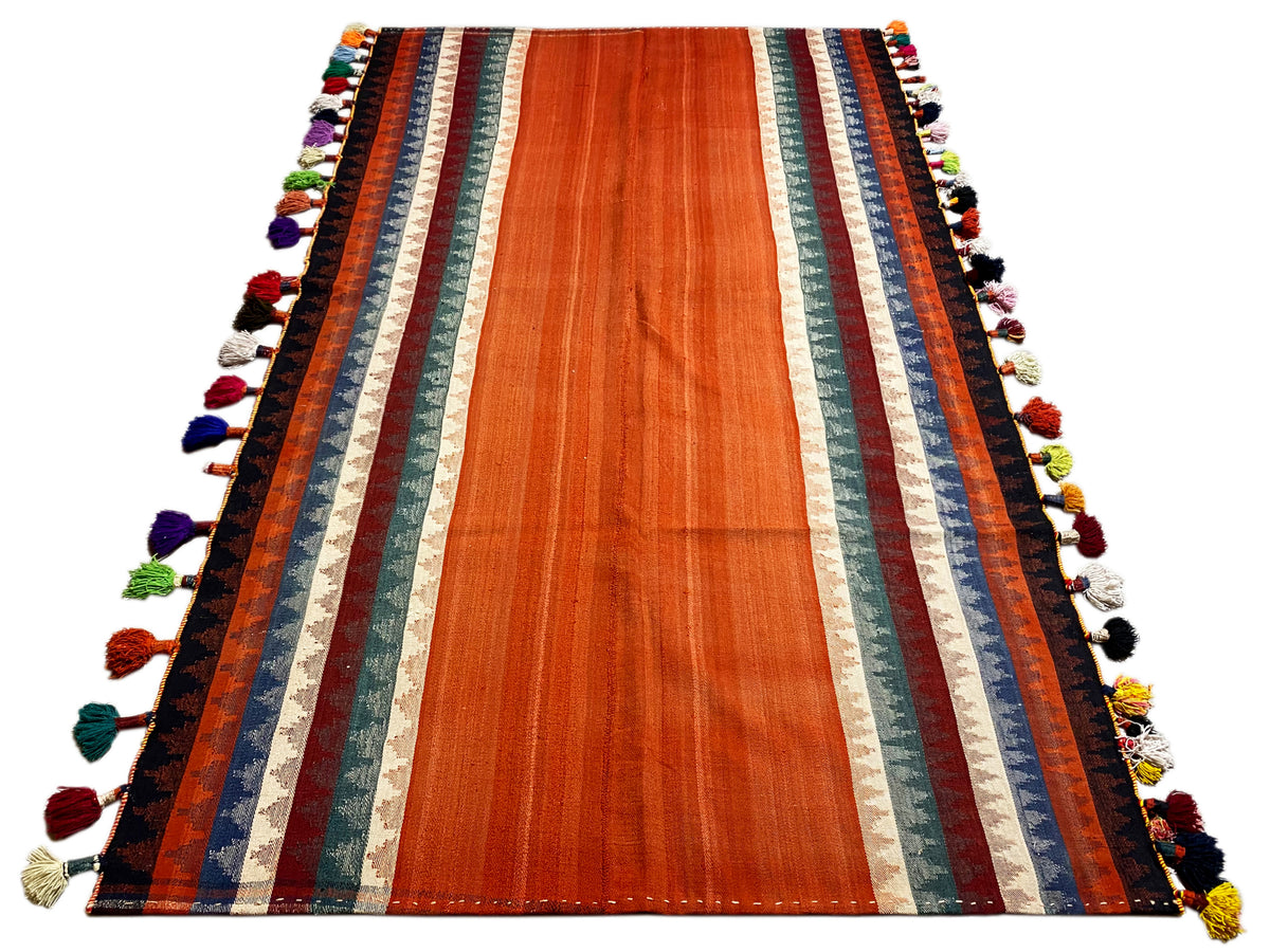 Tapis Jajim terracotta avec bordures à rayures et pompons multicolores le long des bords