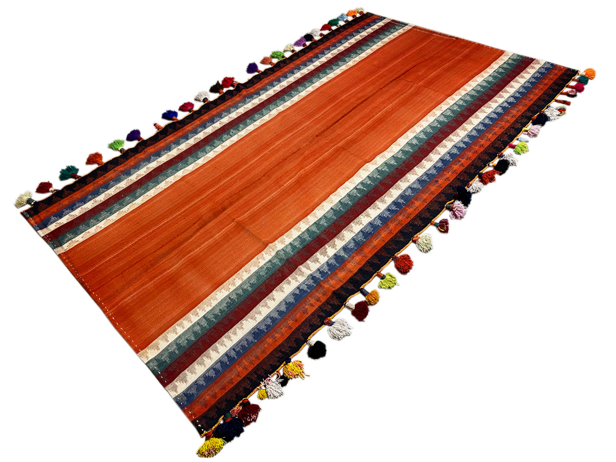 Tapis Jajim diagonal : rayures terracotta, bordure multicolore et pompons à chaque coin