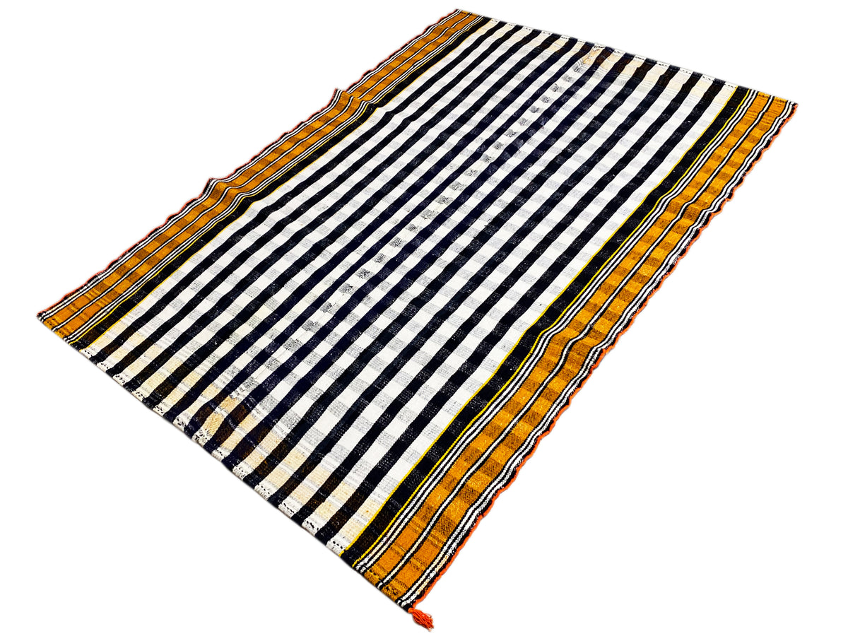 Tapis jajim disposé en diagonale, avec un motif rayé noir et blanc et une bordure orange.