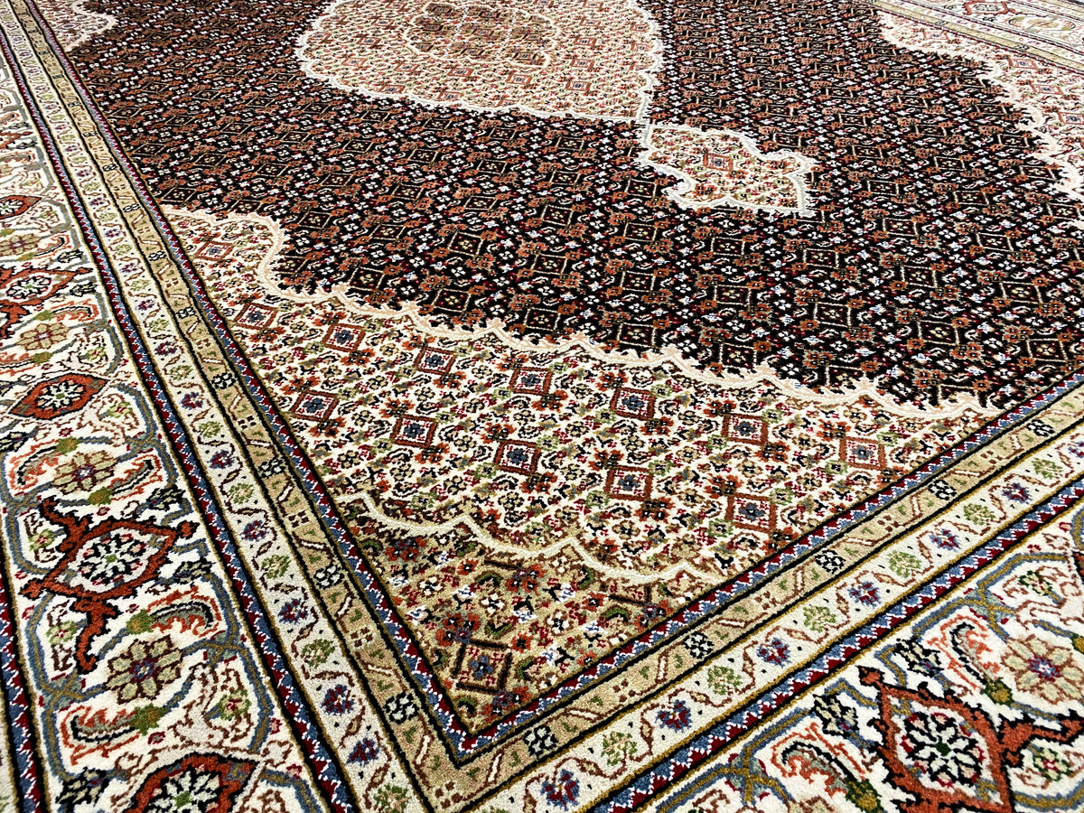 Gros plan sur un tapis indo-tabiz brun : ornements de bordure et motif floral sombre