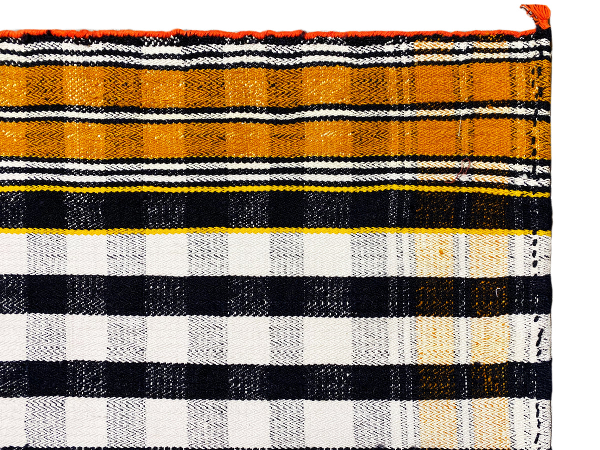 Vue détaillée du tapis Jajim à rayures noires, blanches et orange avec franges