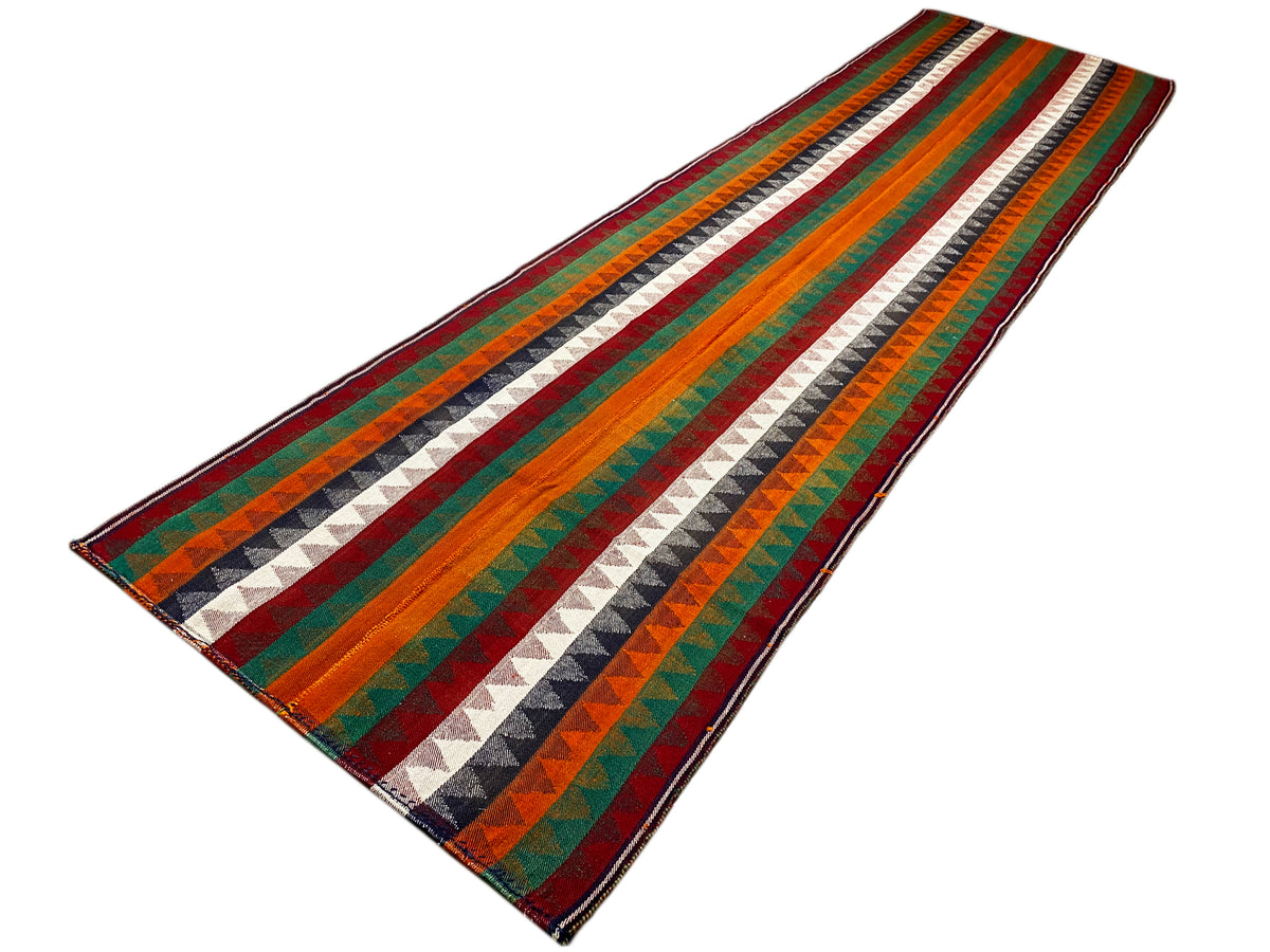 Tapis couloir Jajim posé en biais : rayures multicolores, motif en zigzag, bordure passepoilée