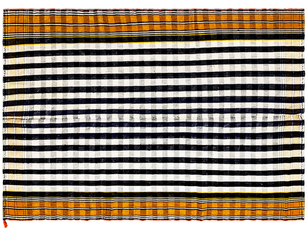 Tapis jajim couvrant une grande surface, avec un motif de rayures quadrillé noir et blanc et une bordure orange.