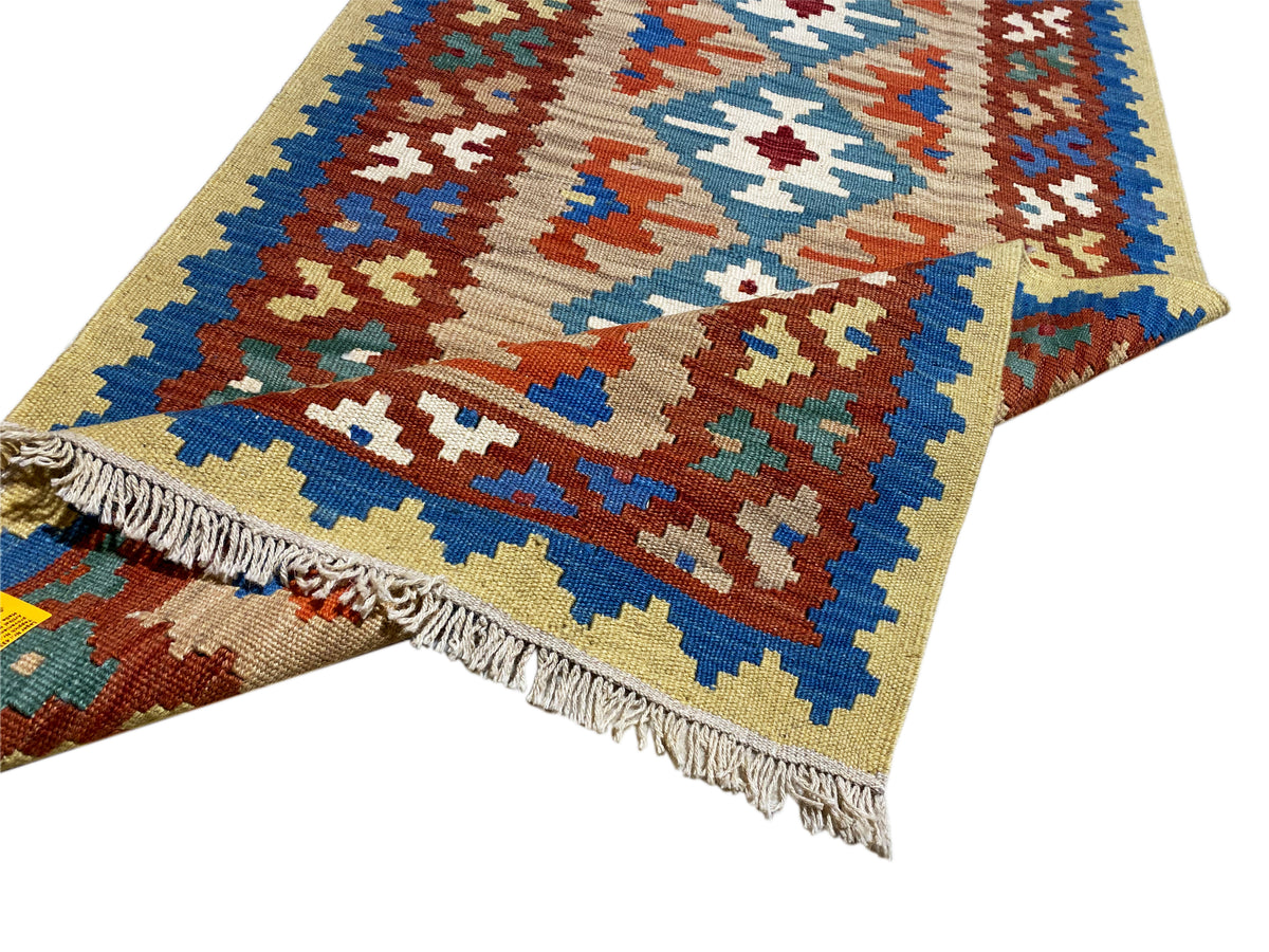 Tapis kilim à franges, orné de motifs colorés en croix et en losanges bleus, orange et verts