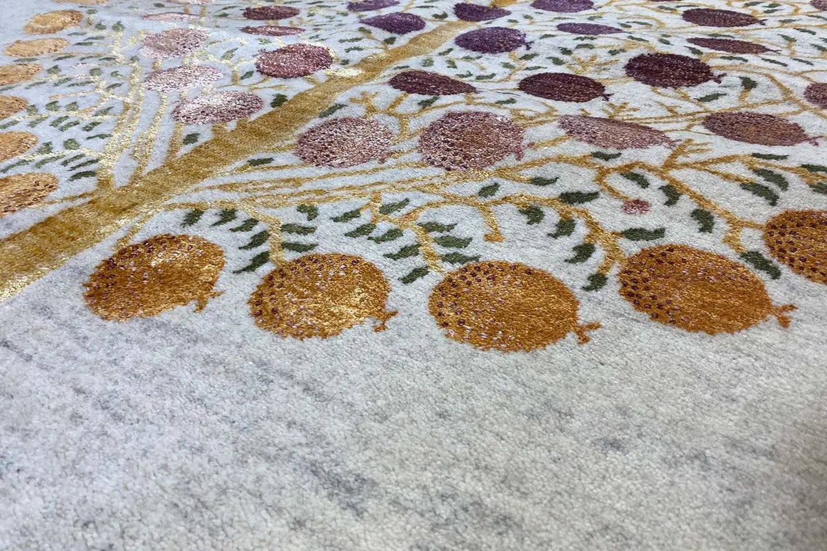 Gros plan d’un tapis Gabbeh : ornements circulaires et arabesques dorées dans des tons violets et bruns sur fond clair