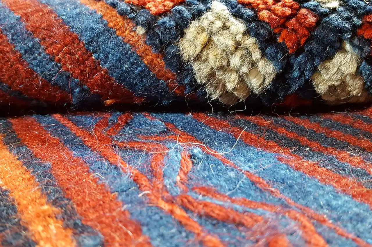 Gros plan sur un tissage kilim : orange, bleu et rouge avec des fils de laine entrelacés