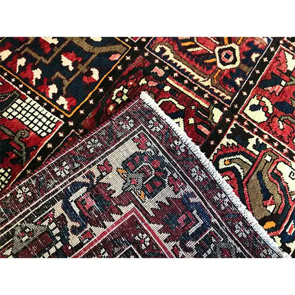 Gros plan sur un tapis oriental Bakhtiari : motifs variés, losanges et motifs en escalier rouge foncé