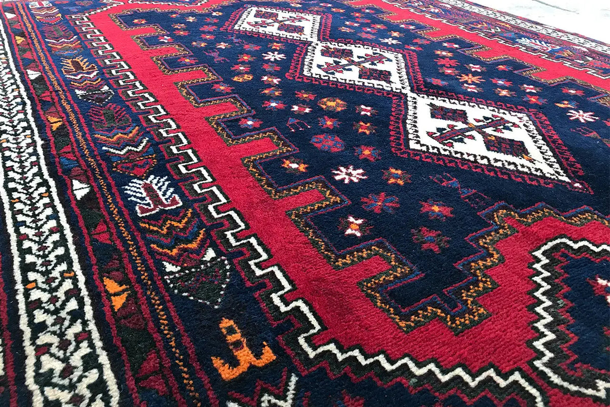 Détail du tapis avec bande centrale rouge et bordure en zigzag bleue et blanche