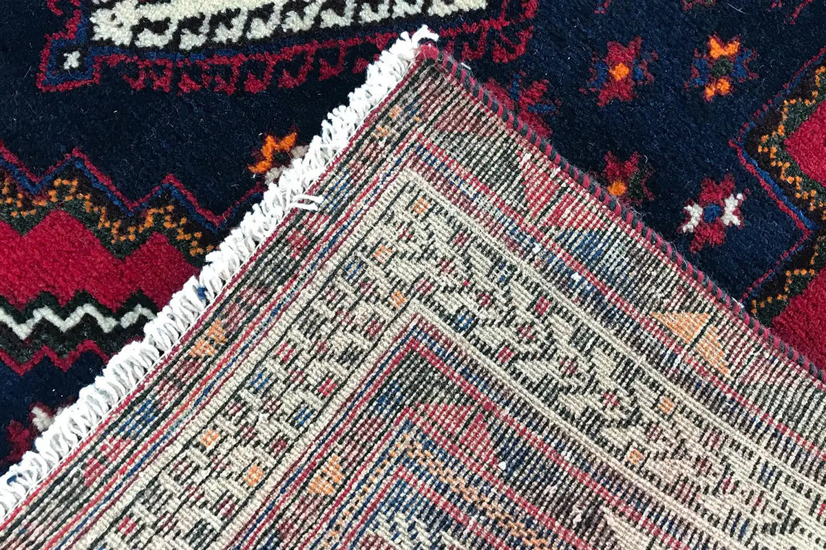 Détail du tapis avec une trame de fond blanc-beige et des ornements colorés
