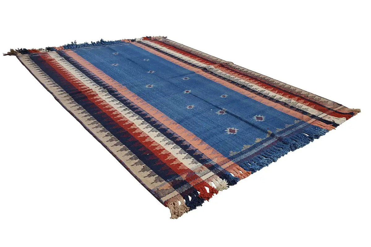 Tapis rayé bleu, rouge et beige, disposé en diagonale avec des franges