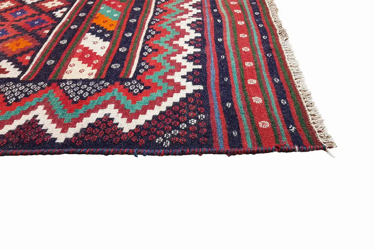 Coin de tapis kilim avec franges et rayures multicolores rouges, bleues, vertes et blanches.