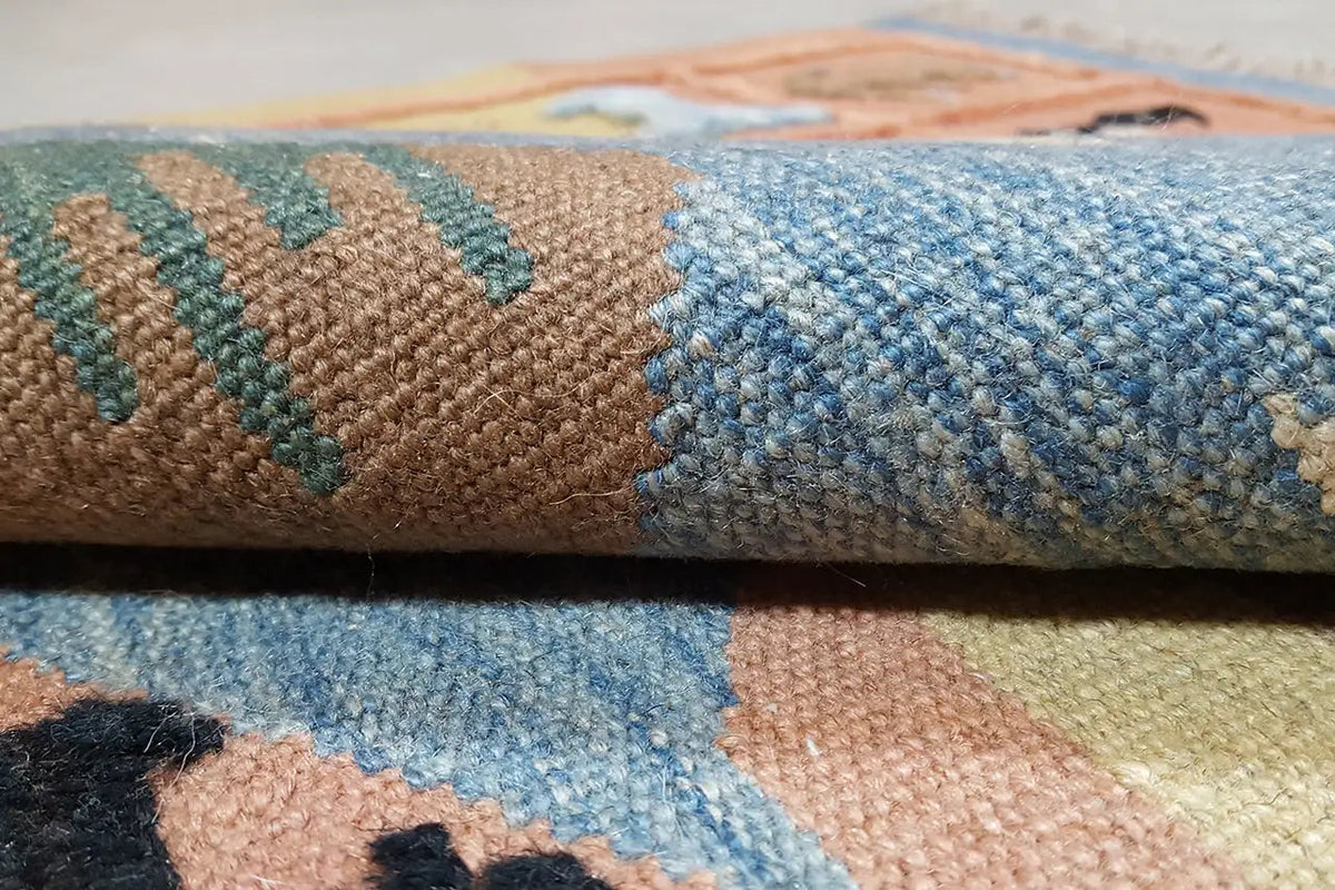 Gros plan : tapis kilim tissé à la main avec un velours bleu et beige, bord latéral