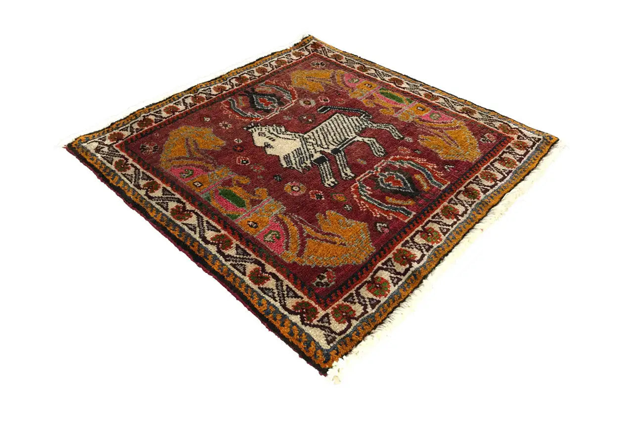 Tapis rectangulaire à fond rouge avec une figure de cheval, bordé d'une bordure