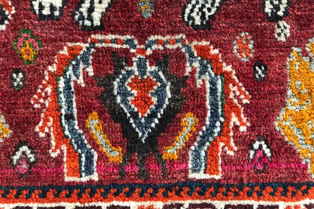 Détail de tapis avec une figure animale blanche stylisée et des ornements rouges et bleus