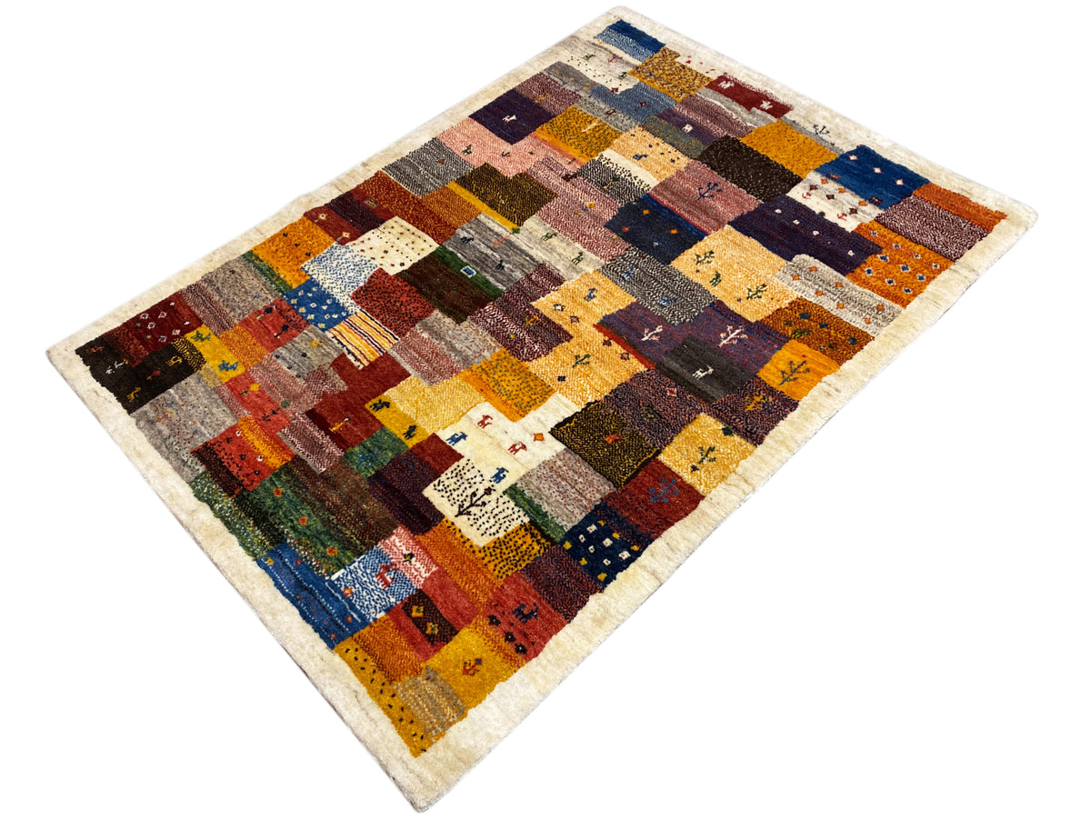 Tapis Gabbeh Luri 145x105 cm en diagonale : carrés patchwork à motifs en rouge, bleu et jaune