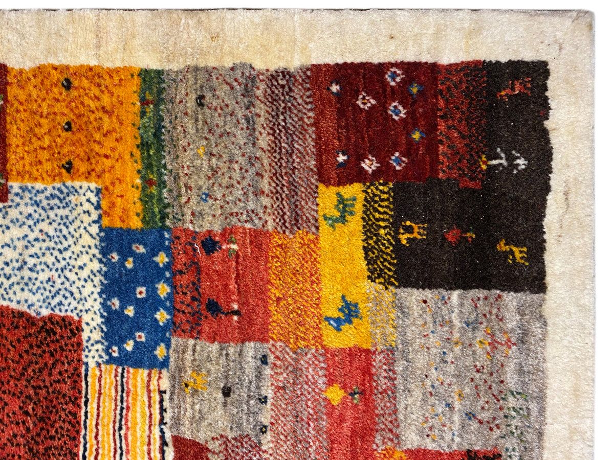 Gros plan sur un tapis Gabbeh Luri de 145x105 cm : motifs patchwork orange, jaunes et bleus