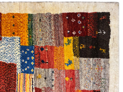 Gros plan sur un tapis Gabbeh Luri de 145x105 cm : motifs patchwork orange, jaunes et bleus