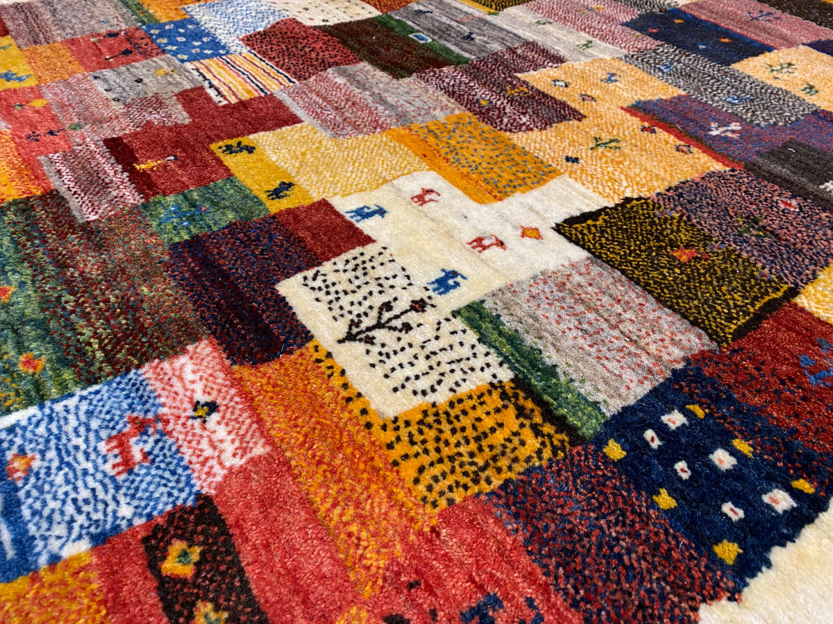 Gros plan d’un tapis Gabbeh Luri de 145x105 cm : blocs de patchwork colorés et bordure claire