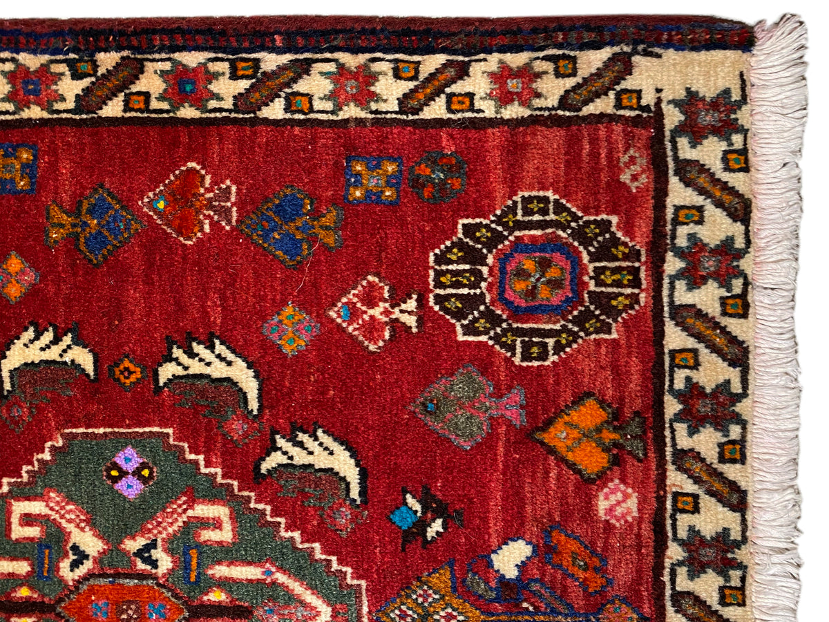 Vue rapprochée du tapis Poshti 58x57 cm : poil rouge avec motifs ornementaux et bordure à franges