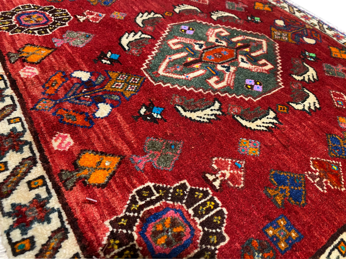 Gros plan sur le tapis Poshti 58x57 cm, motif rouge avec des motifs animaliers et floraux