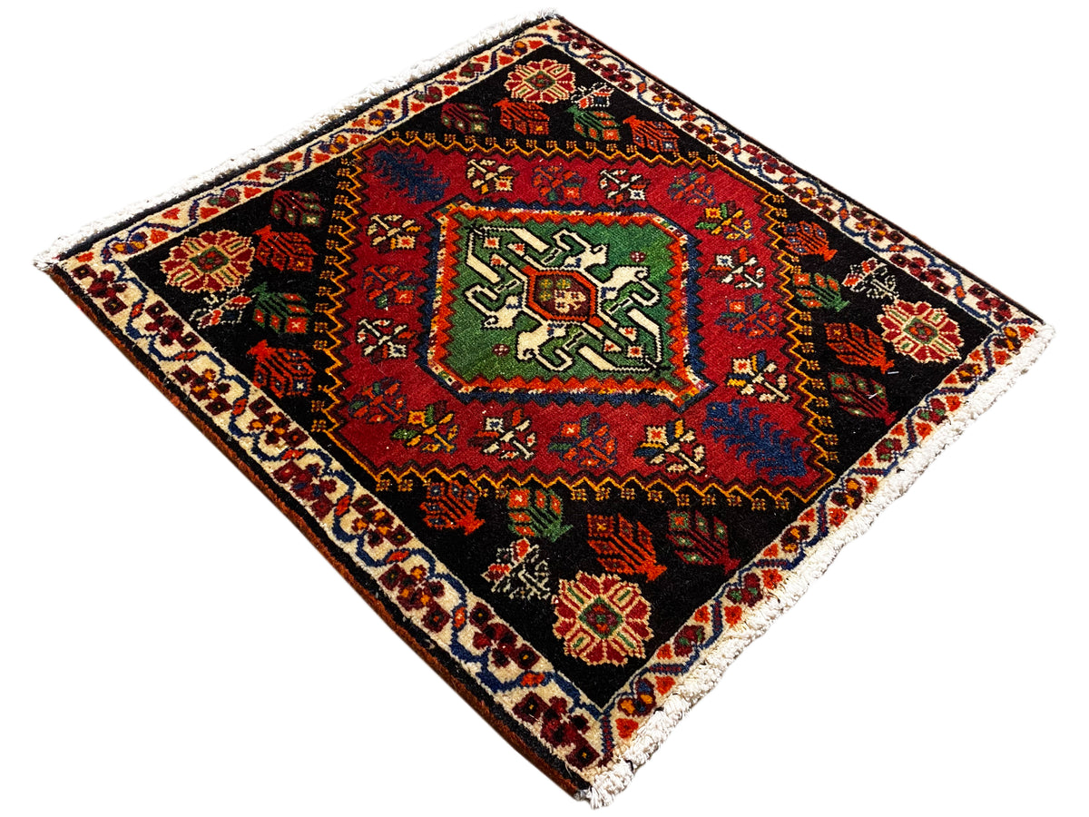 Tapis Poshti carré, en diagonale : tapis noir avec médaillon vert et bordure colorée