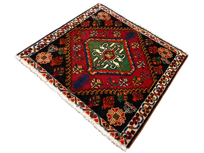 Tapis Poshti carré, en diagonale : tapis tissé noir avec motif central vert-rouge