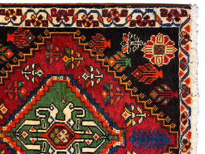 Gros plan d’un tapis Poshti : tapis noir avec médaillon vert et ornements colorés