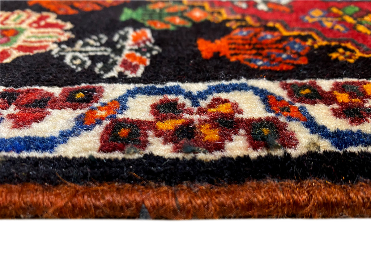 Détail de bordure du tapis Poshti : bordure multicolore et poil du tapis au bord inférieur