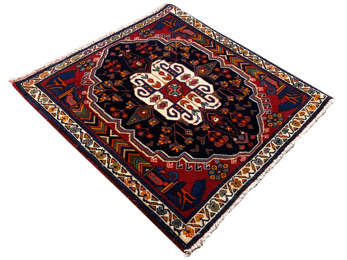 Tapis Poshti à motif losanges, fond sombre et ornement central blanc