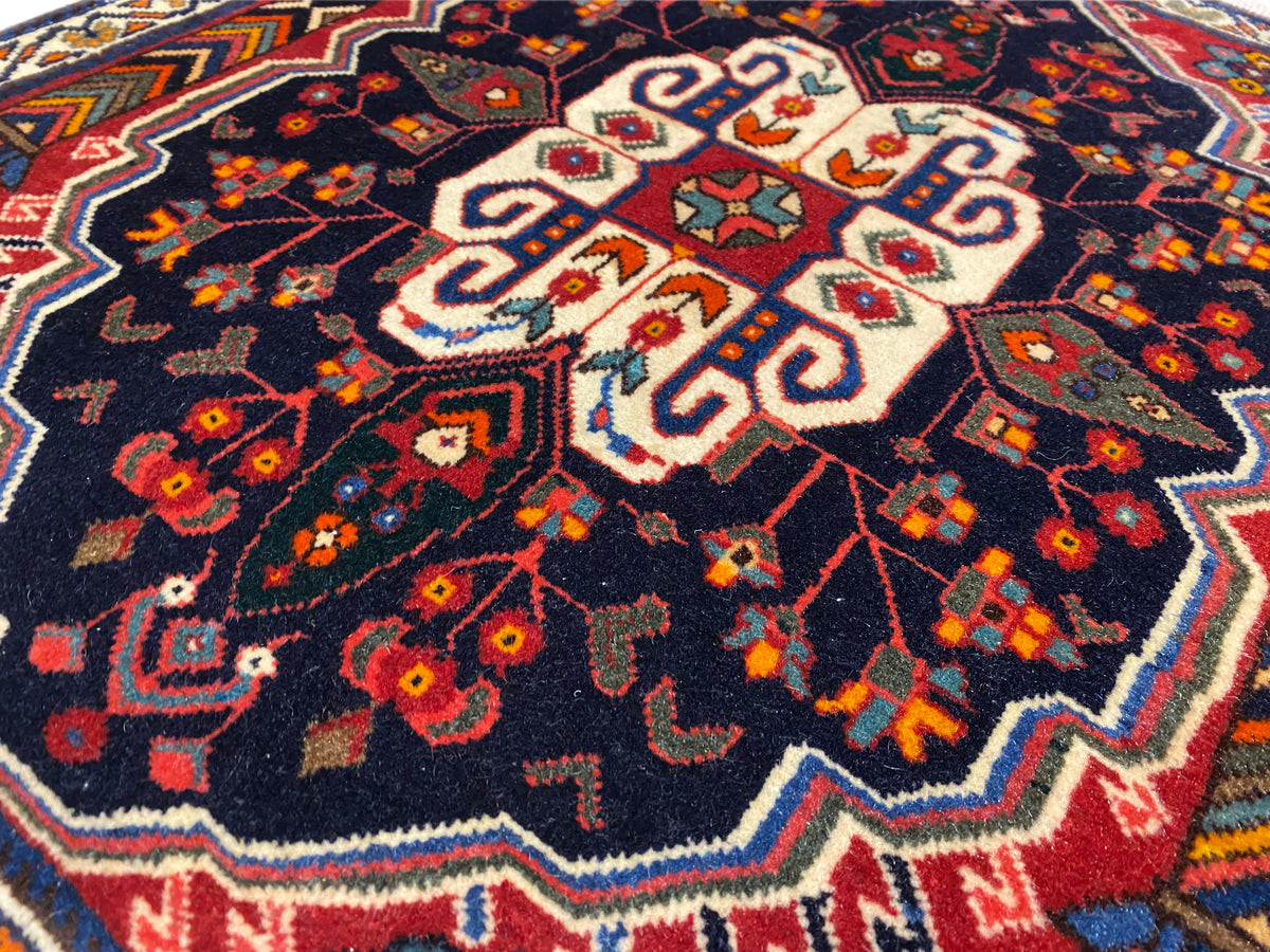 Gros plan détaillé d’un tapis Poshti : motif central blanc sur fond bleu foncé