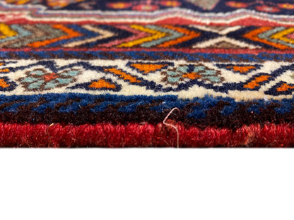 Gros plan du tapis Poshti sur le bord, avec une hauteur de poil dense et une bordure rouge