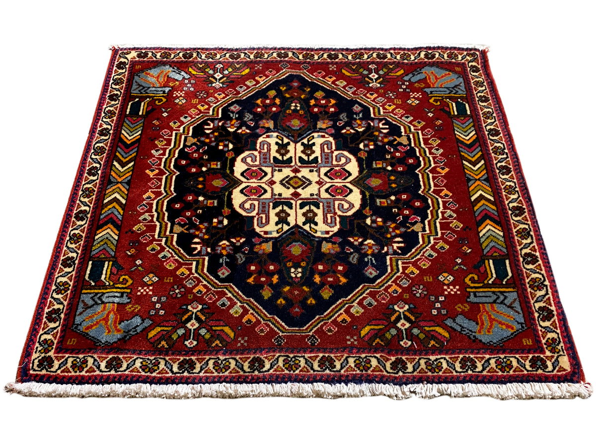 Tapis Poshti à fond rouge et médaillon symétrique, surface contrastante bleu-noir
