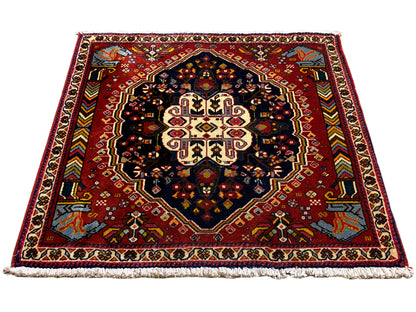 Tapis Poshti à fond rouge et médaillon symétrique, surface contrastante bleu-noir