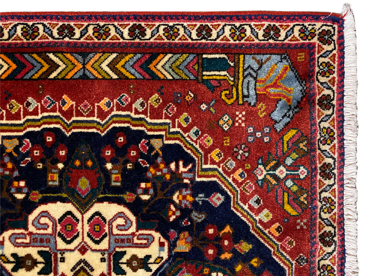 Détail de la bordure du tapis Poshti avec des ornements rouges, bleus et jaunes