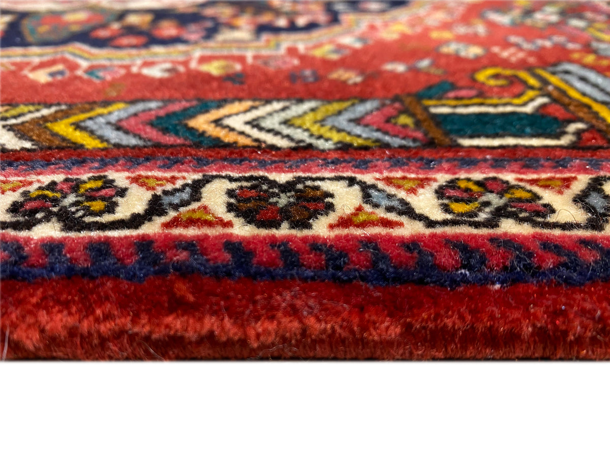Détail de la bordure du tapis Poshti avec des franges rouges et bleues et des motifs tissés