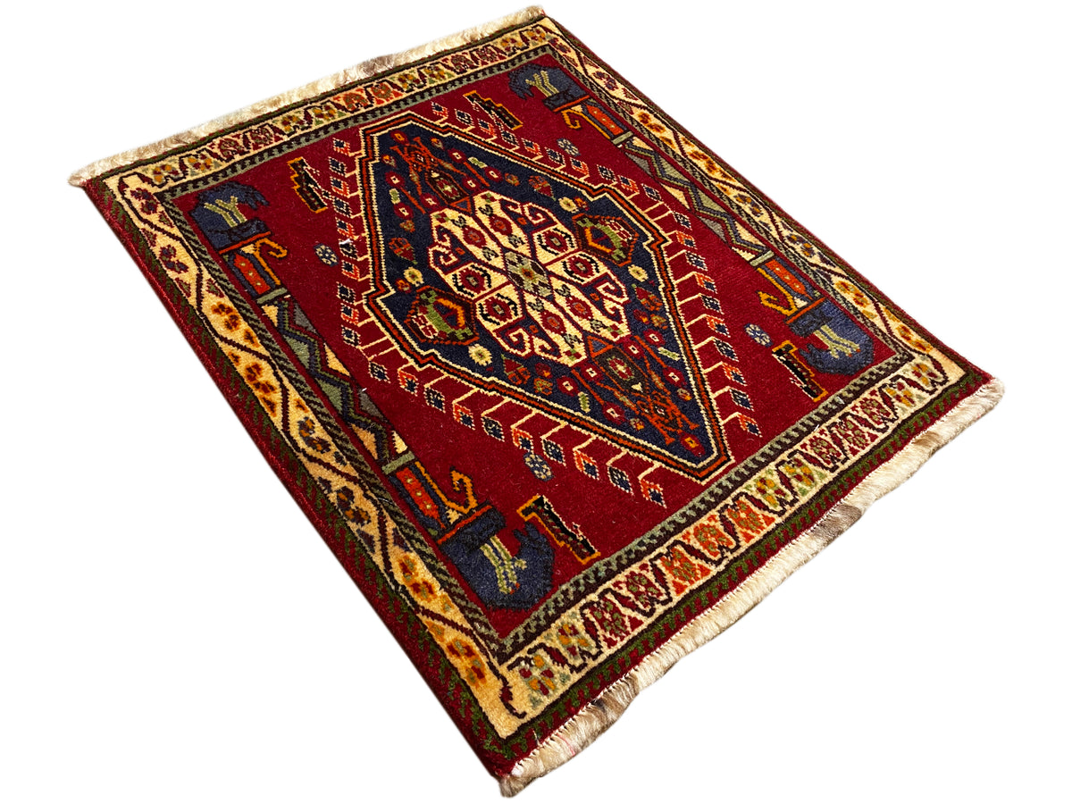 Tapis Poshti (59×61 cm) déployé en diagonale, motif géométrique rouge avec franges