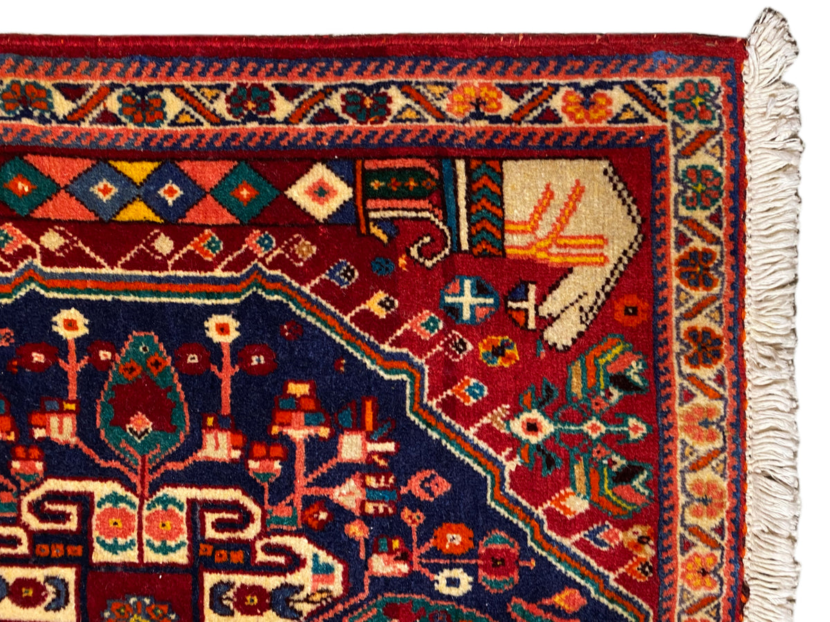 Tapis Poshti 64x64 cm, gros plan sur la bordure aux motifs géométriques, rouge-bleu, pompons