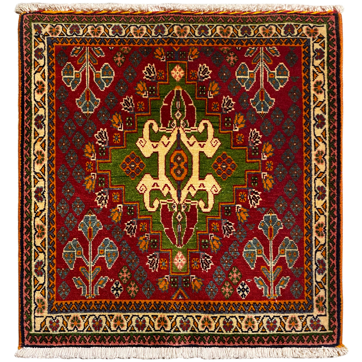 Tapis oriental aux motifs aux couleurs vives rouge, verte et beige, de forme carrée avec franges