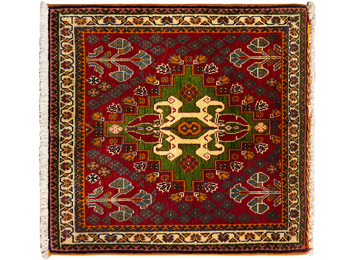 Tapis oriental à fond rouge, motif de médaillons vert et beige avec bordure périphérique, franges