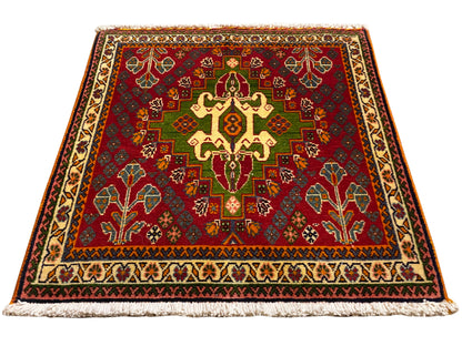 Tapis oriental avec motif central rouge, détails verts et bordure beige, avec franges