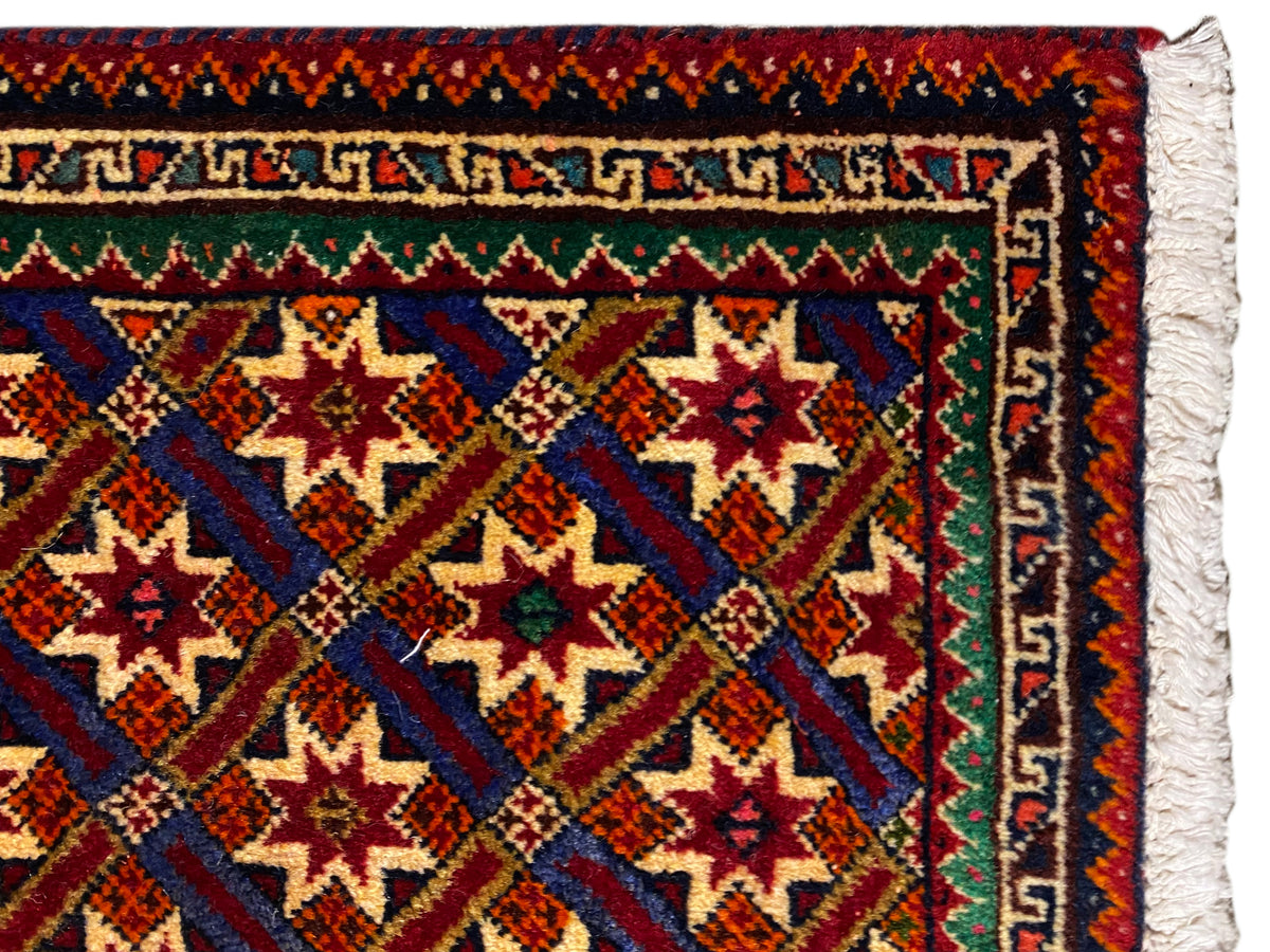 Tapis Poshti 62x52 cm en gros plan : bordure, motifs rouges et bleu-vert, et franges blanches.
